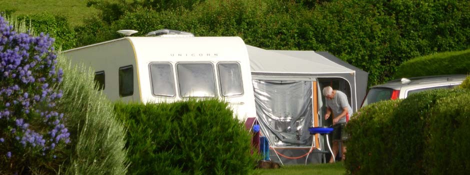 gentleman cooking on a gas griddle outside a caravan and awning