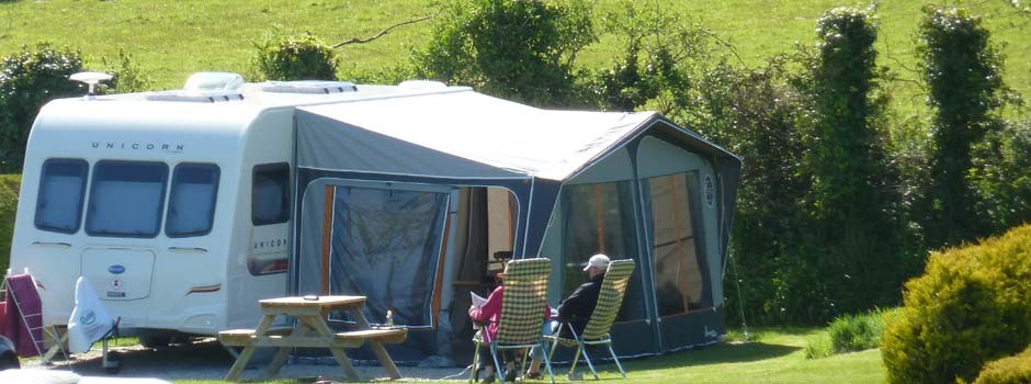 couple sat outside a caravan and awning on pitch 18