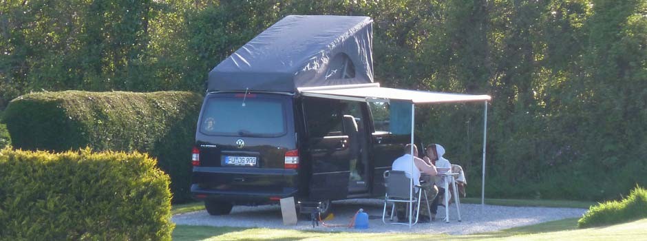 people sat eating outside a foreign campervan on pitch 22