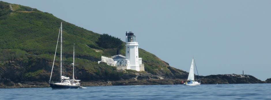 St Anthony's lighthouse from the water with boats sailing past in front