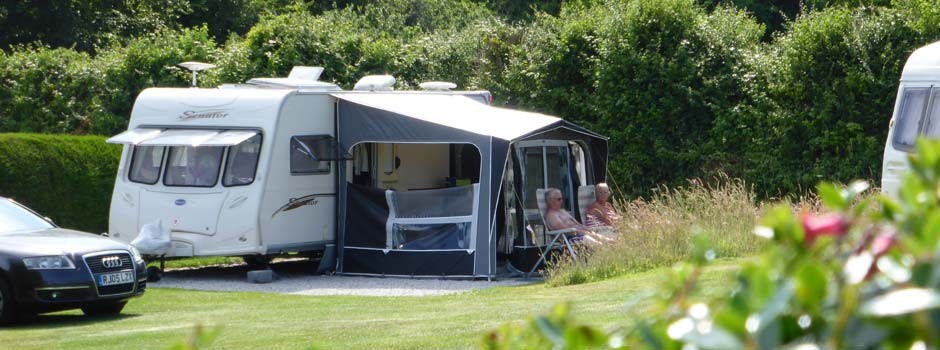 couple sat outside a caravan and awning on pitch 20