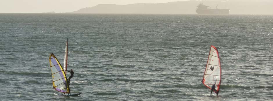 three wind-surfs out on the water in Falmouth bay