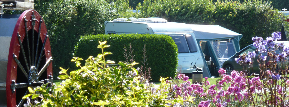 caravan and awning on pitch 60 with water wheel and flowers in the foreground